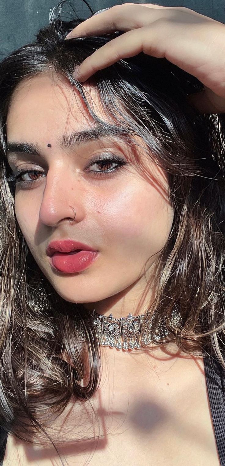 a close up of a person wearing a choker and posing with her hair blowing in the wind