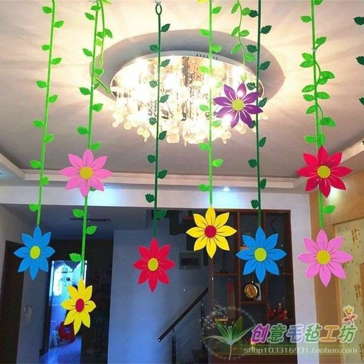 colorful paper flowers hanging from the ceiling in a room with chandelier and lights