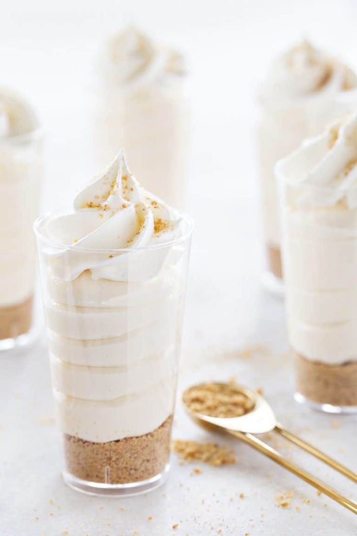 four dessert cups with whipped cream and cinnamon sprinkles in them on a table