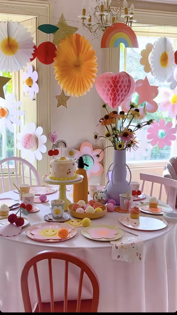 a table topped with plates covered in cake next to a vase filled with flowers and balloons