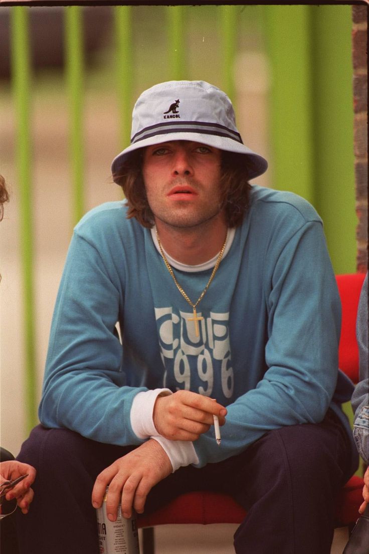 two men sitting next to each other with hats on their heads and one wearing a blue shirt