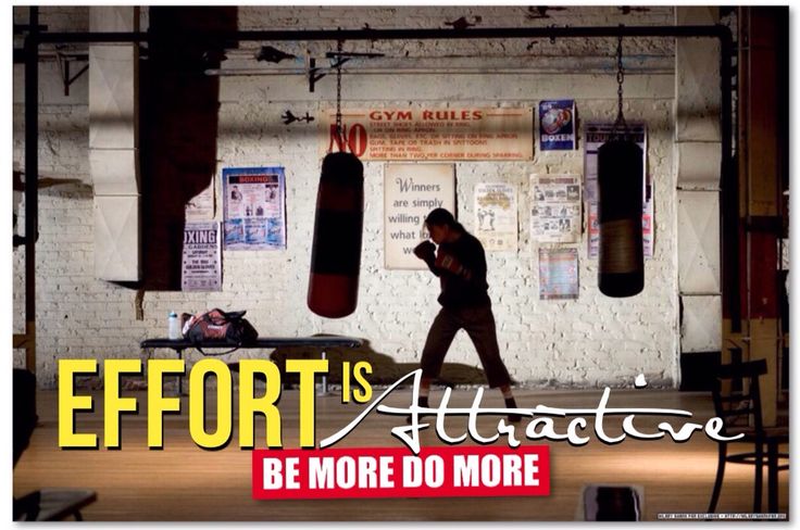 a man walking through a gym holding a cell phone to his ear as he walks past punching bags