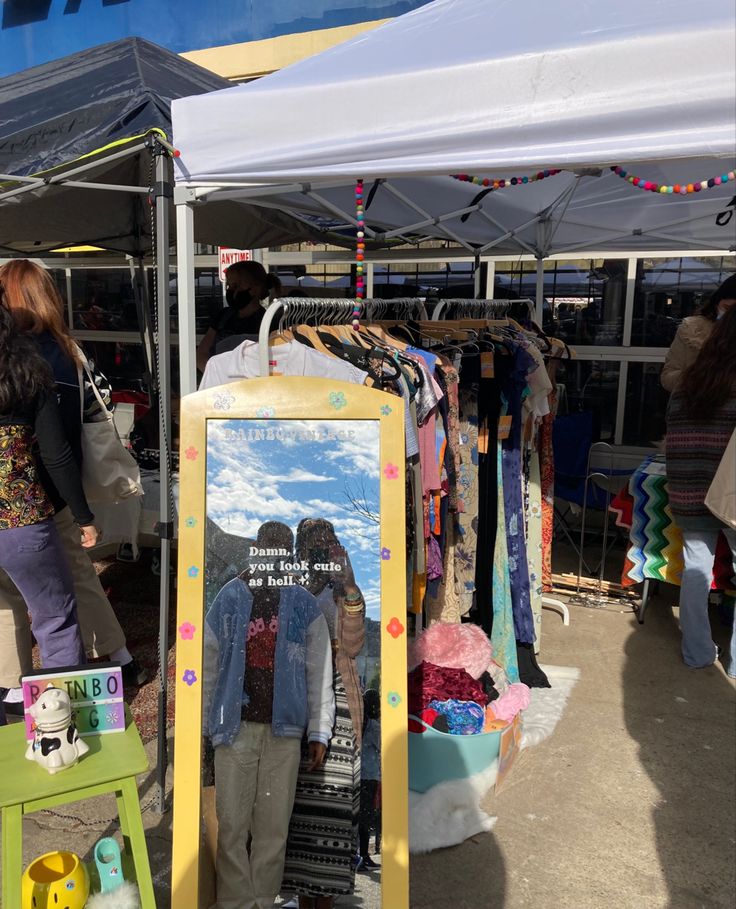 a man and woman are standing in front of a sign that is advertising clothes for sale