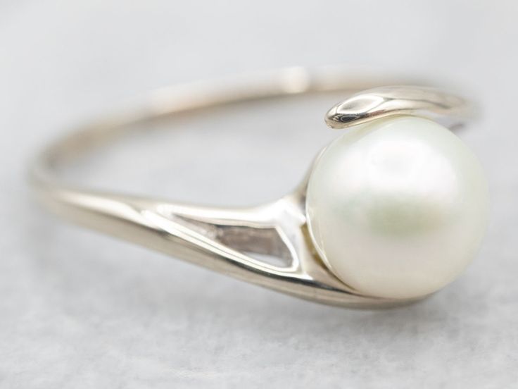 This beautiful, bypass-designed white gold ring is an amazing and feminine statement ring! The big, luscious pearl is cultured, measuring 7.7mm round and with lovely, soft pink iridescence. This would make a perfect piece as a right-hand ring on a Wedding Day - something that could be worn over and over for years to come.Metal: 14K White GoldGem: PearlGem Measurements: 7.4 mm, RoundRing Size: 9.50Marks: "\S/ 14K" Stamped on the inside band Classic White Bypass Ring For Formal Occasions, Elegant Pearl Ring With Polished Finish For Wedding, White Gold Bypass Ring With Polished Finish For Wedding, Elegant Silver Bypass Ring For Formal Occasions, Elegant Silver Bypass Ring For Formal Events, Elegant White Gold Bypass Ring, Elegant Bypass Promise Ring, Elegant Wedding Bypass Ring, Round Polished Pearl Wedding Ring