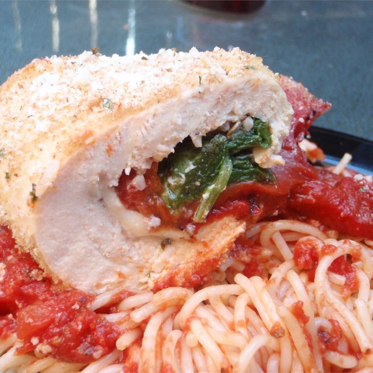 a close up of a plate of food with pasta and meat on it, including chicken parmesan