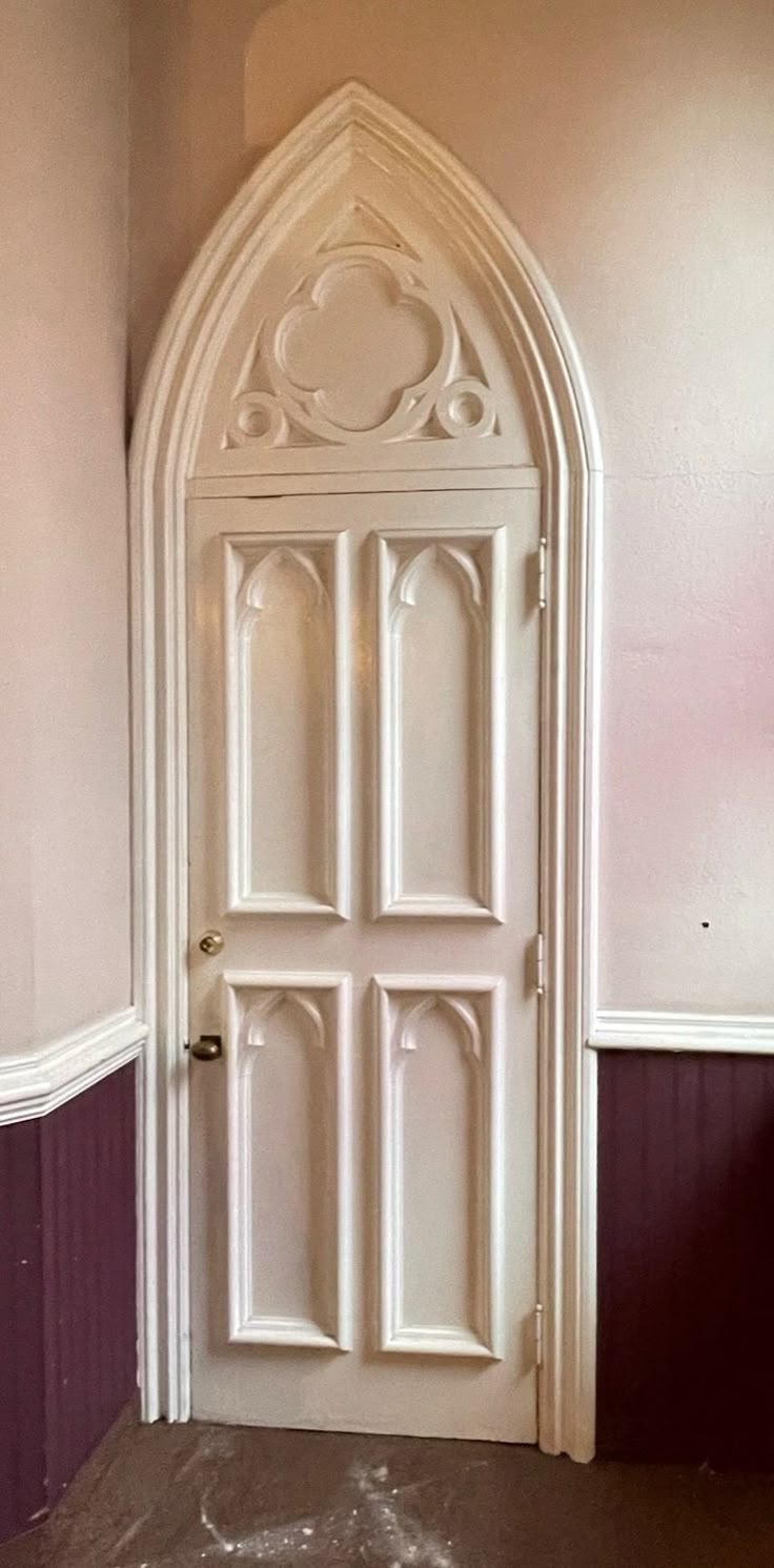 a white door in the corner of a room with purple walls and wood trimming