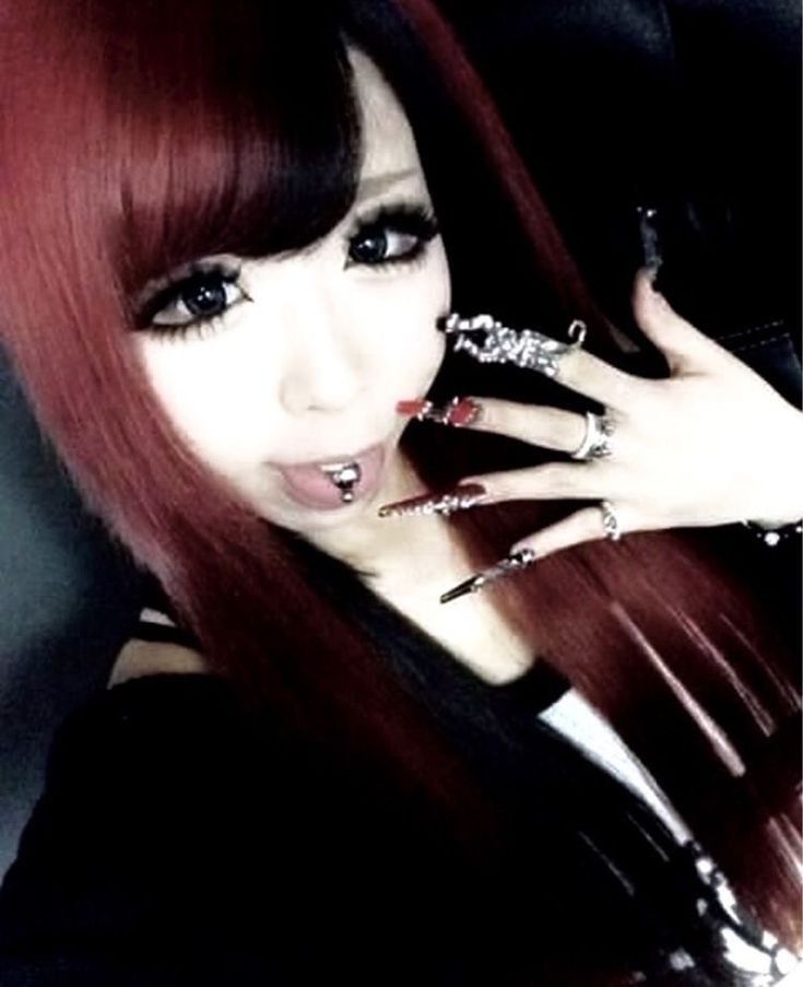 a woman with long red hair and piercings on her fingers