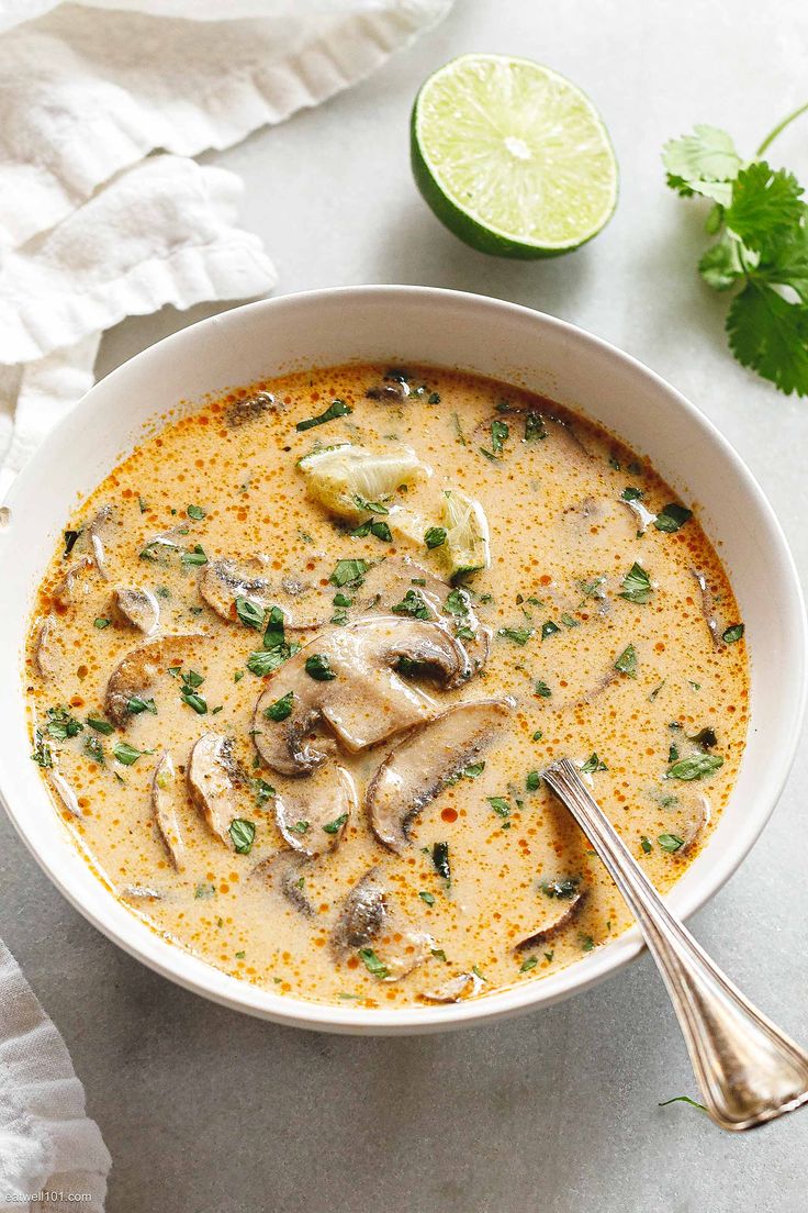 a white bowl filled with soup and garnished with cilantro, green onions and mushrooms