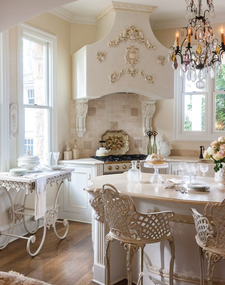 a white kitchen with chandelier, table and chairs in front of the stove