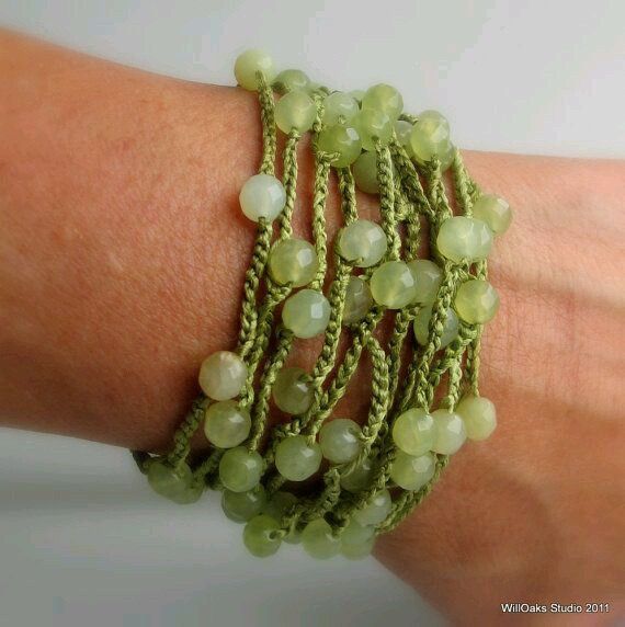 a close up of a person's arm wearing green bracelets with beads on it