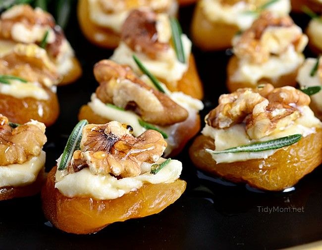 small appetizers with walnuts and cream cheese on a black plate, ready to be eaten