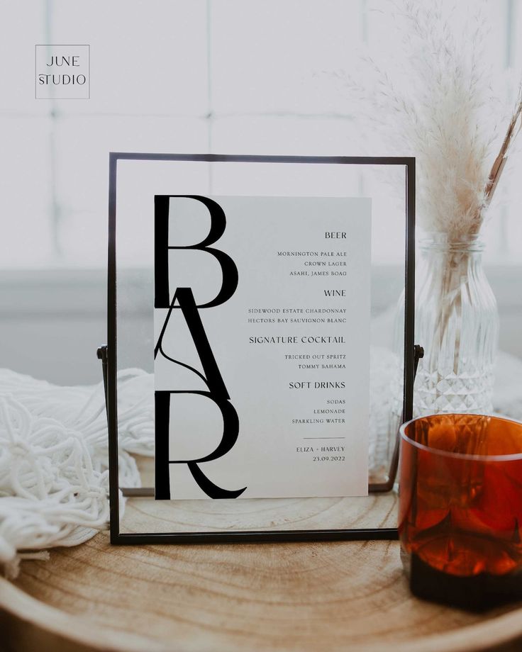 a table with a glass and some type of paper on it next to a candle