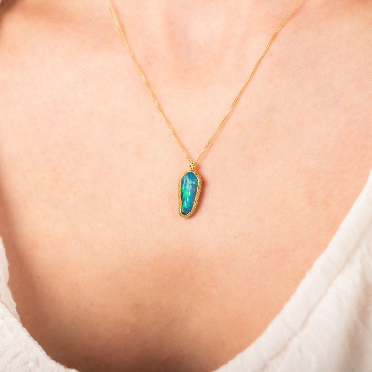 This blue-green Ethiopian Opal looks like a glowing leaf from a fairytale land. Hand-carved with intricate detail, this one-of-a-kind gemstone is set in a handmade gold bezel accented with braided gold. Technical Details Metal: 18k yellow goldEthiopian Opal: 1.98 cts. Pendant Size (not including bail): 15x 7mmChain: can be worn at 16" and 18"Closure: lobster claspHandmade in New YorkStyle # N-3047-OP Artisan Yellow Gold Gemstone Jewelry, Nature-inspired Yellow Gold Jewelry With Gemstone, One Of A Kind Oval Yellow Gold Jewelry, 14k Gold Nature-inspired Oval Jewelry, Oval 14k Gold Nature-inspired Jewelry, Nature-inspired 14k Gold Oval Jewelry, Nature-inspired Oval 14k Gold Jewelry, Unique Yellow Gold Jewelry For May Birthstone, Nature-inspired Opal Jewelry Gift