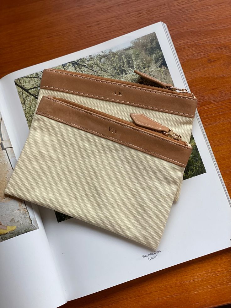 an open book sitting on top of a wooden table next to a purse and wallet