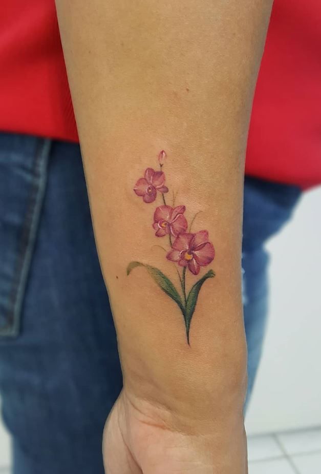 a small pink flower tattoo on the wrist