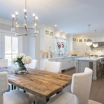 a dining room table surrounded by white chairs and an island in the middle of a kitchen