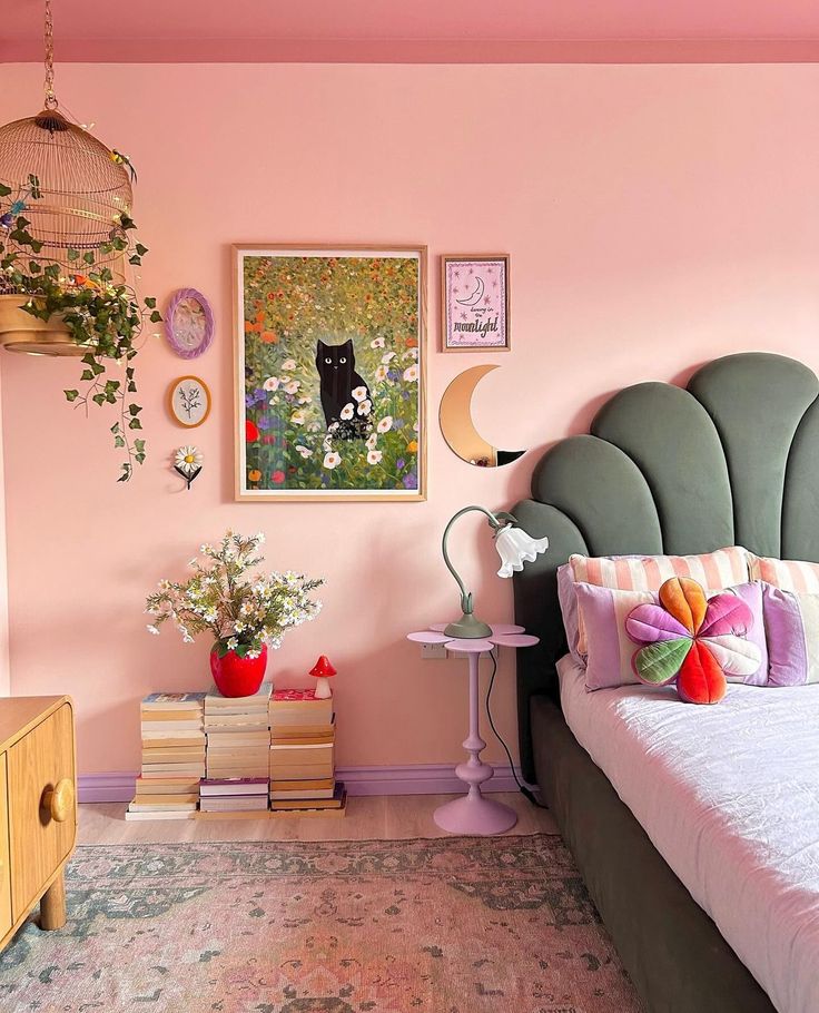 a bedroom decorated in pink and green with a cat on the headboard, bookshelf