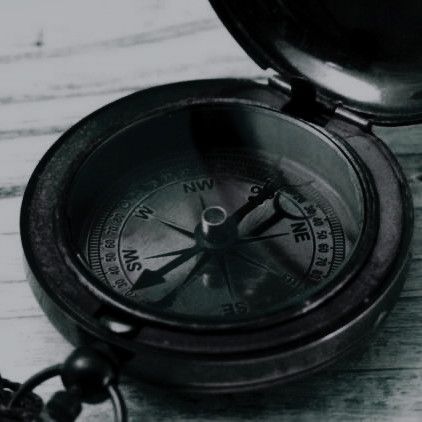 an old brass compass sitting on top of a white wooden table next to a chain