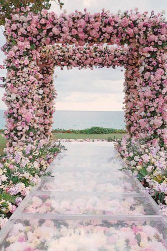 an outdoor wedding ceremony with pink and white flowers on the aisle leading to the ocean