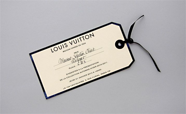 a pair of scissors and a tag on a white surface with the words louis vuitton printed on it