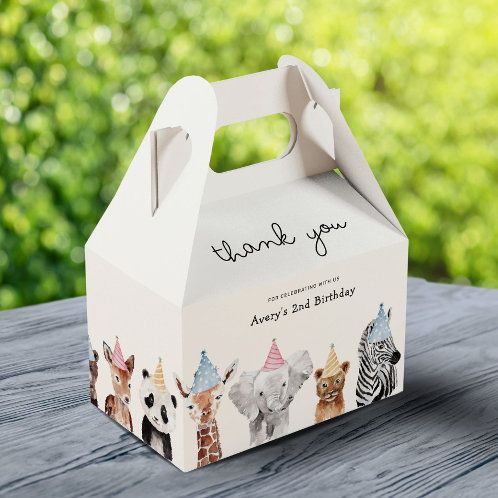 a white box with animals on it sitting on top of a wooden table next to trees