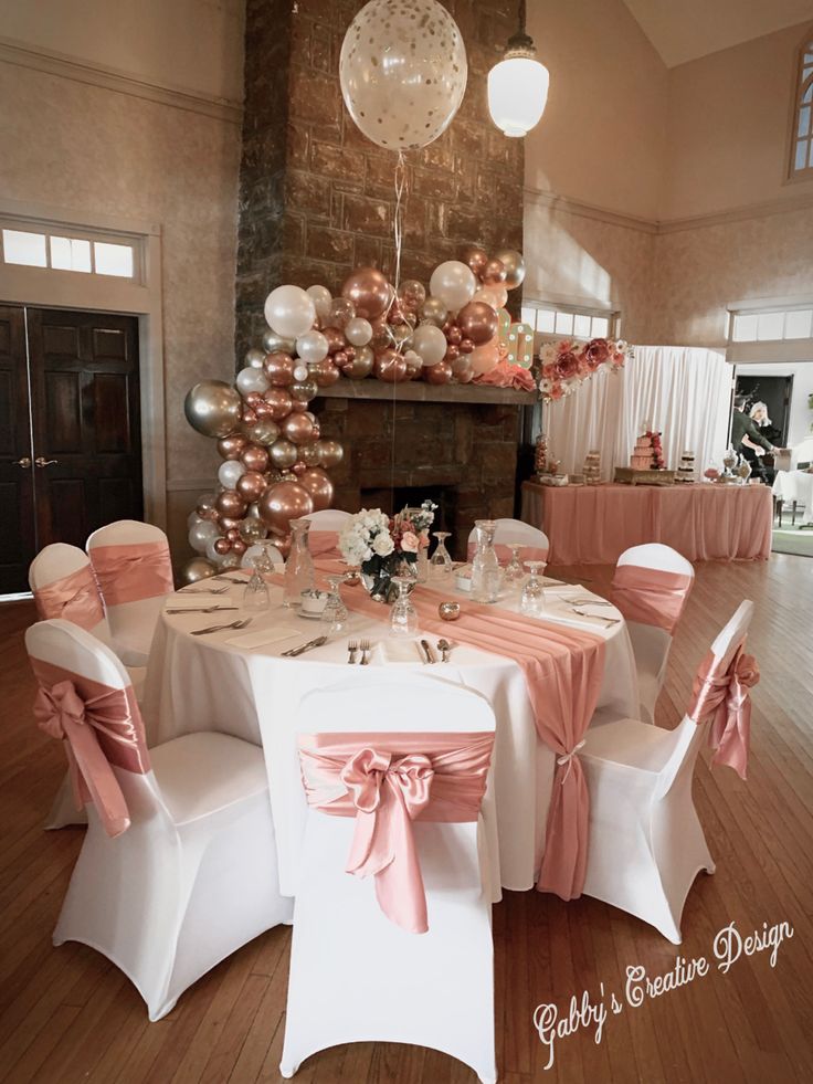 a room filled with tables covered in white and pink table cloths next to a fire place