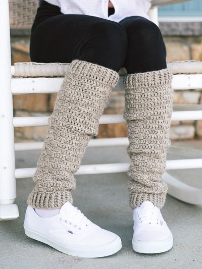 a woman sitting on top of a white chair wearing knitted leg warmers