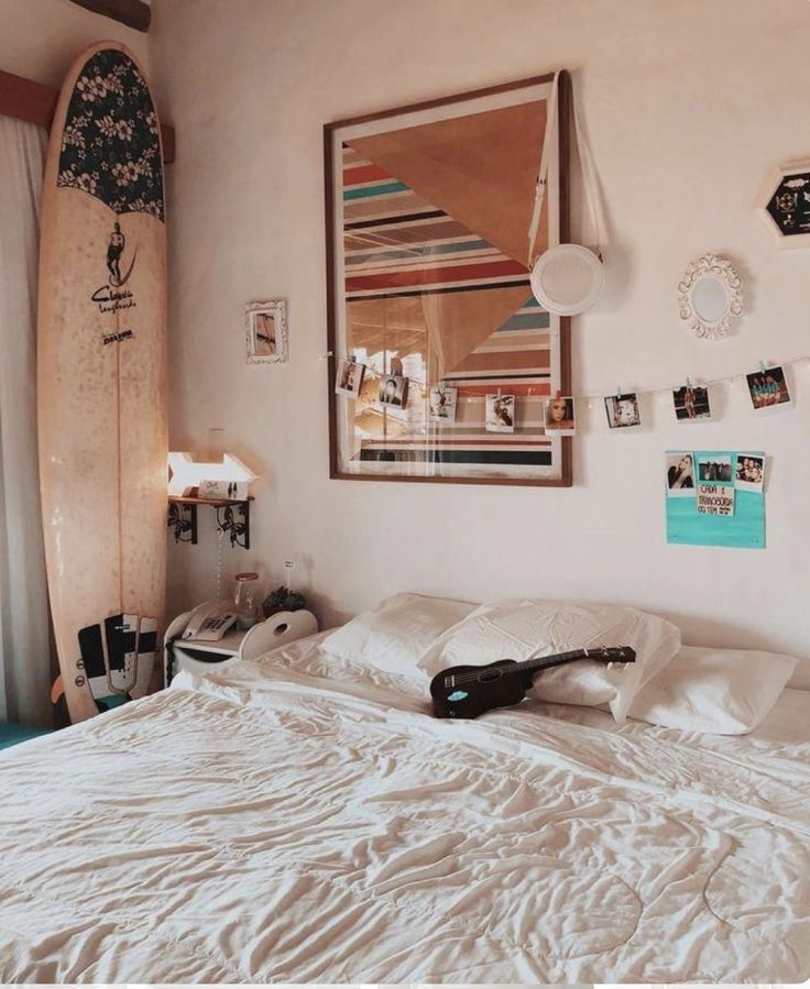 a surfboard is hanging on the wall next to a bed with white sheets and pillows