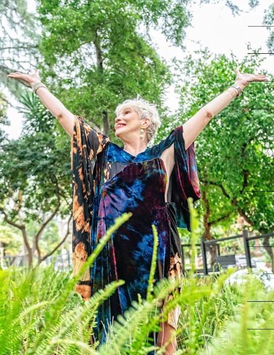 a woman standing in the grass with her arms outstretched