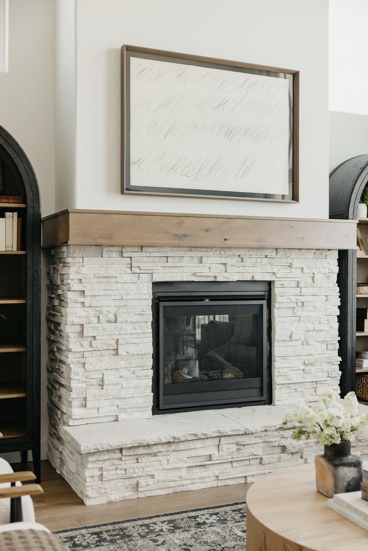 a living room with a fire place and bookshelves on the wall above it