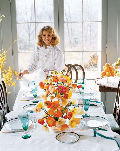 a woman sitting at a table with flowers on it