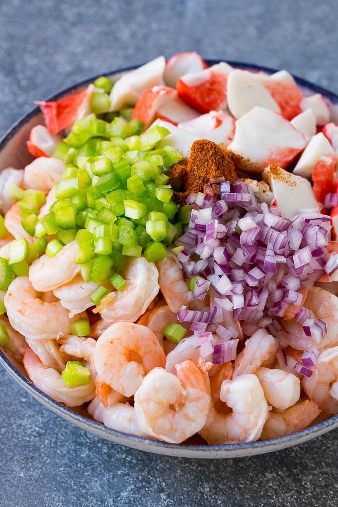 a bowl filled with shrimp and vegetables on top of a gray countertop next to a knife