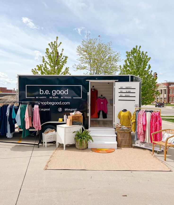 a mobile clothing store with clothes hanging on the rack and an open door that says be good