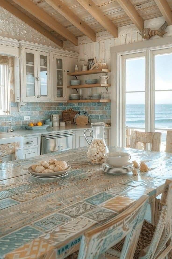 a kitchen with a table and chairs next to the ocean