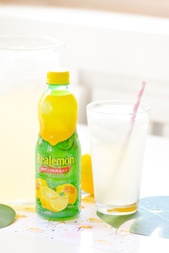 a bottle of lemonade sitting next to a glass filled with milk and orange slices