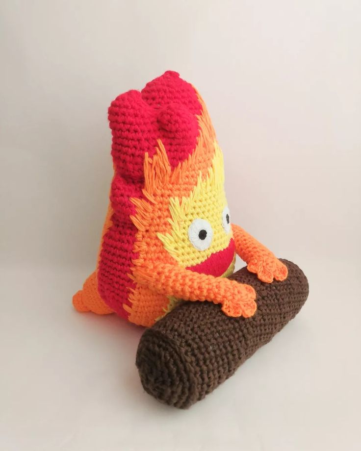 a crocheted stuffed animal sitting on top of a piece of wood