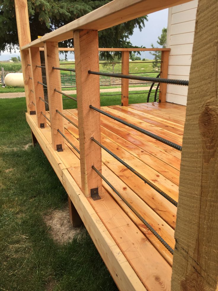 a wooden deck with metal railings in the grass