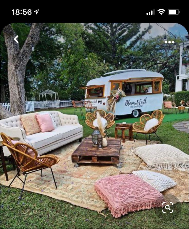 an outdoor area with chairs, couches and a camper in the back ground