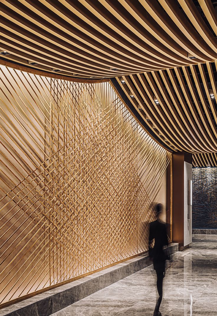 a person walking down a hallway with wooden slats on the wall