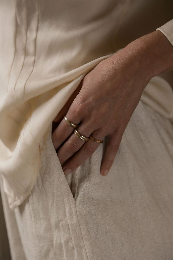 a close up of a person's hand with two rings on their fingers and wearing pants