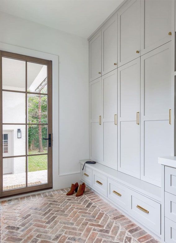 an empty room with white cabinets and brick flooring