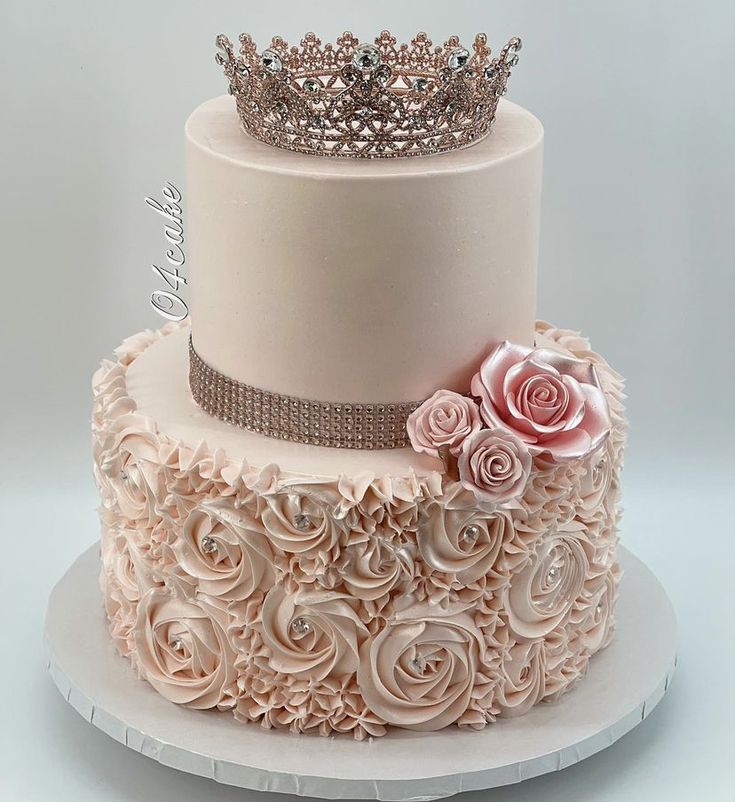 a three tiered cake with roses and a tiara on top that is sitting on a plate