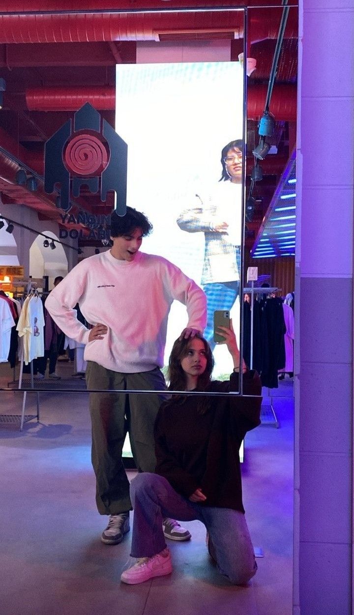 a man and woman standing next to each other in front of a display case with mannequins