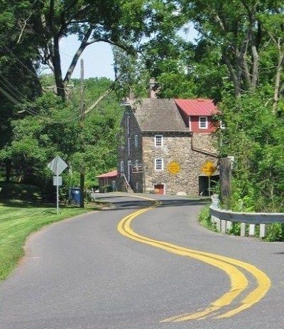 a winding road with a stone house in the background