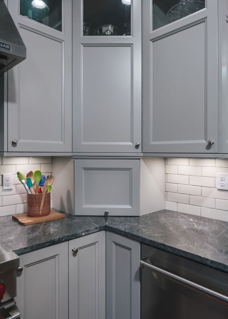 a kitchen with gray cabinets and marble counter tops