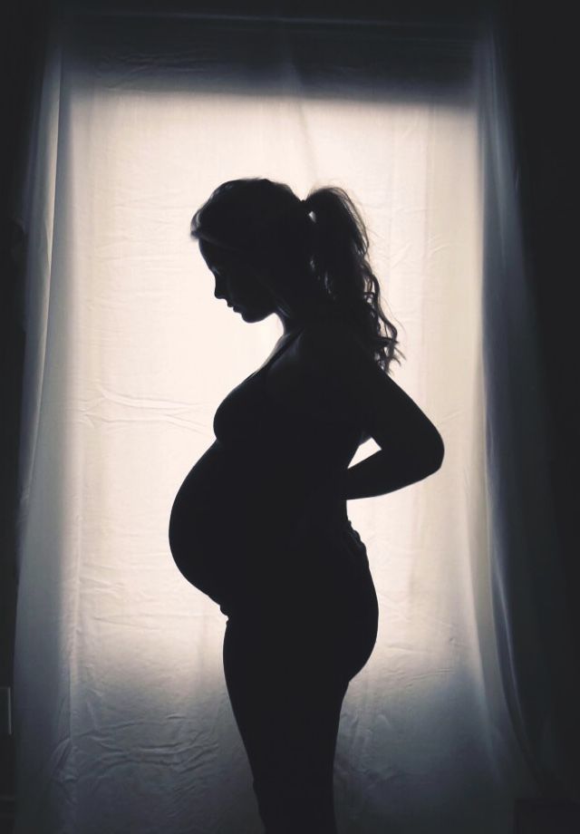 a pregnant woman standing in front of a window