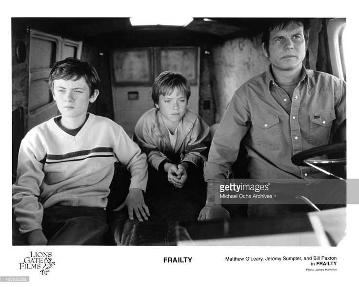 three people sitting in the back of a boat with one man looking at the camera