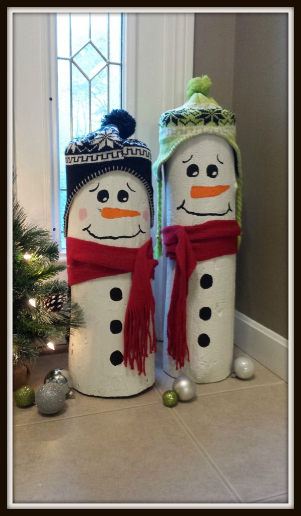 two snowmen standing next to each other in front of a christmas tree and window