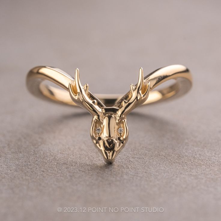 a gold ring with a deer's head on the front, and two diamonds in the middle