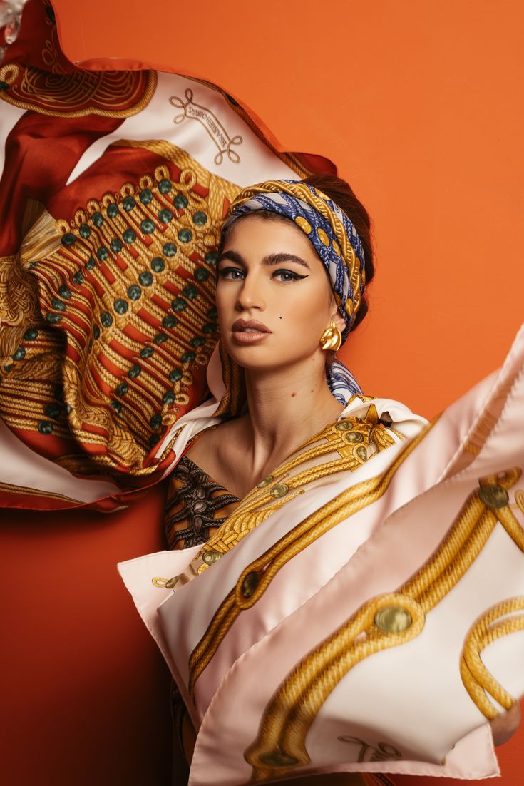 a woman with an elaborate headdress is posed in front of a red wall